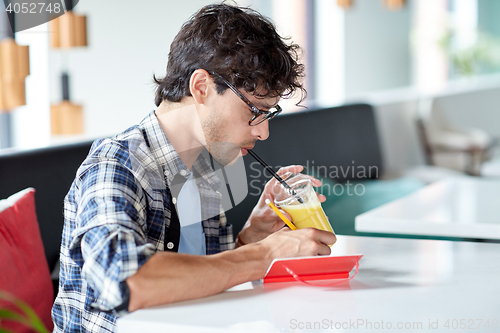 Image of man with notebook and juice writing at cafe