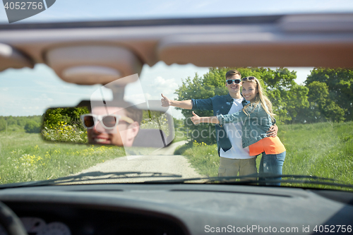 Image of couple hitchhiking and stopping car on countryside