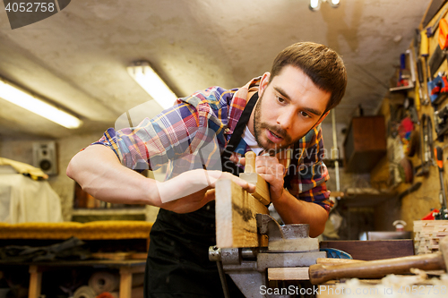 Image of carpenter working with plane and wood at workshop