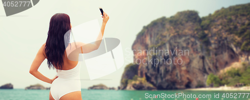 Image of young woman taking selfie with smartphone on beach