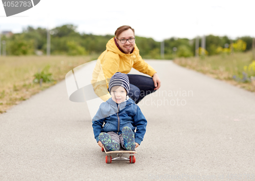 Image of happy father and little son riding on skateboard