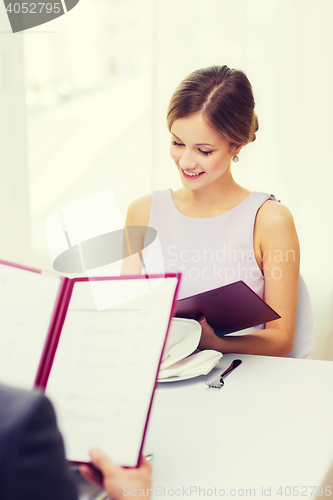 Image of smiling young woman looking at menu at restaurant