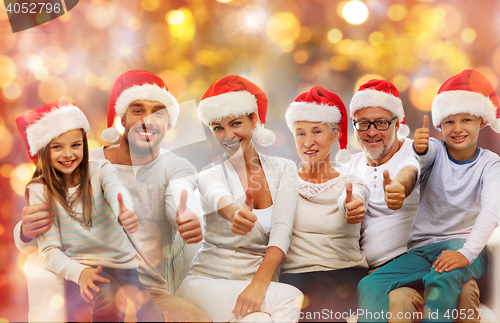 Image of happy family in santa hats showing thumbs up