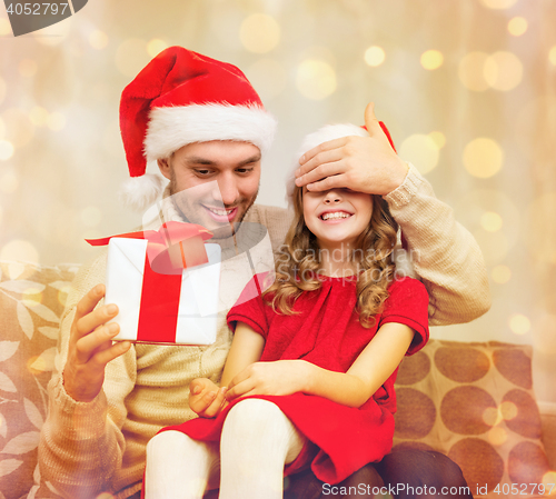 Image of smiling father surprises daughter with gift box