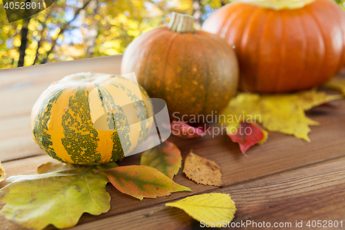 Image of close up of pumpkins on wooden table outdoors