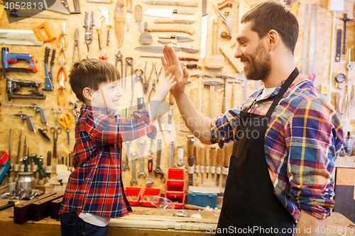 Image of father and little son making high five at workshop