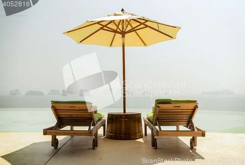 Image of infinity pool with parasol and sun beds at seaside