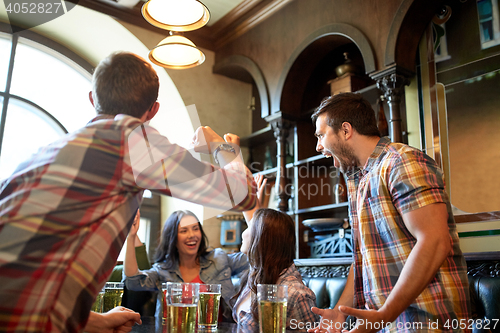 Image of happy friends with beer celebrating at bar or pub