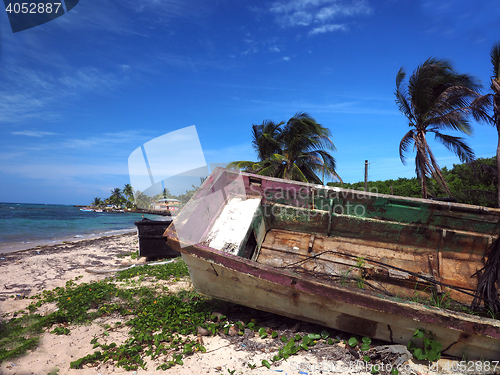 Image of wooden fishing boat rotting on beach with hotel in background No