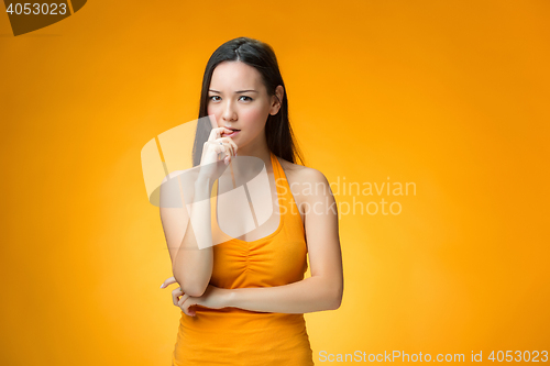 Image of The thinking Chinese girl on yellow background