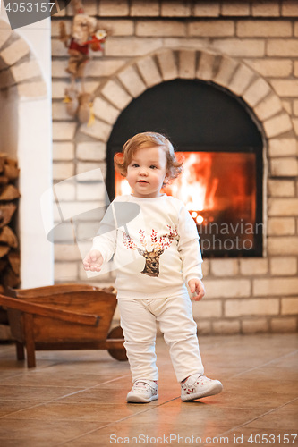 Image of Happy child little girl standing at home against fireplace