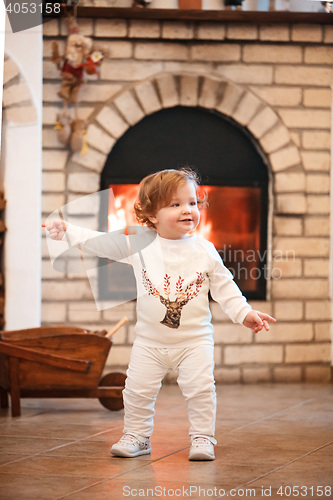 Image of Happy child little girl standing at home against fireplace