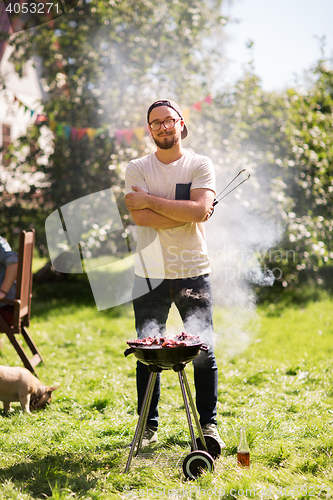 Image of man cooking meat on barbecue grill at summer party