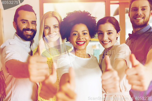 Image of happy creative team showing thumbs up in office