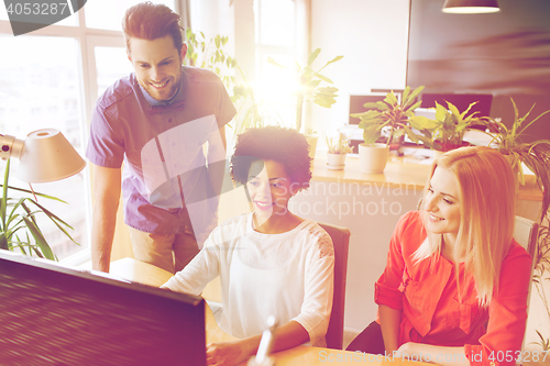 Image of happy creative team with computer in office