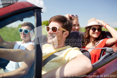 Image of happy friends driving in cabriolet car