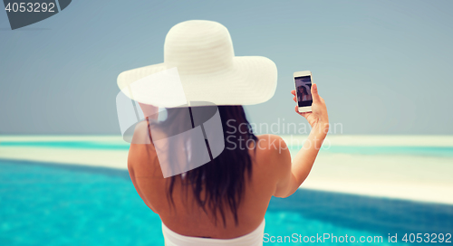 Image of smiling young woman taking selfie with smartphone