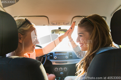 Image of happy teenage girls or women driving in car