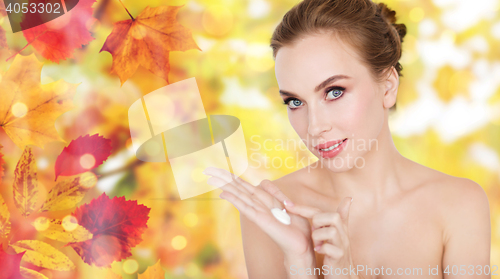 Image of happy young woman with moisturizing cream on hand