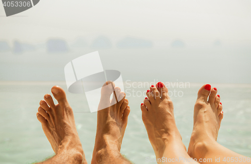 Image of closeup of couple feet over sea and sky on beach