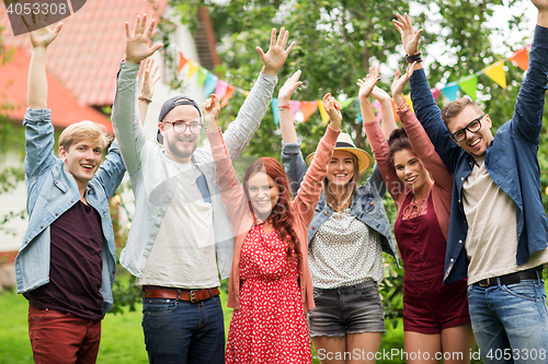 Image of happy teen friends waving hands at summer garden