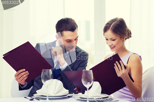 Image of smiling couple with menus at restaurant