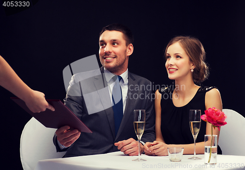 Image of waiter giving menu to happy couple at restaurant