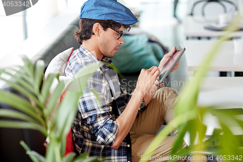 Image of man with tablet pc sitting at cafe table
