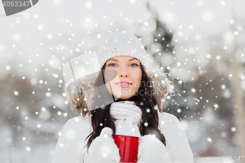 Image of happy young woman with tea cup outdoors in winter