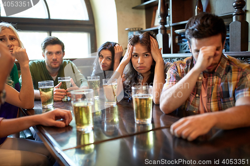 Image of friends with beer watching football at bar or pub