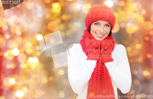 Image of happy woman in hat, scarf and mittens over lights