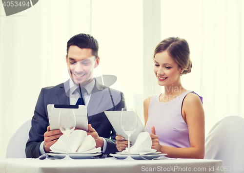 Image of couple with menus on tablet pc at restaurant