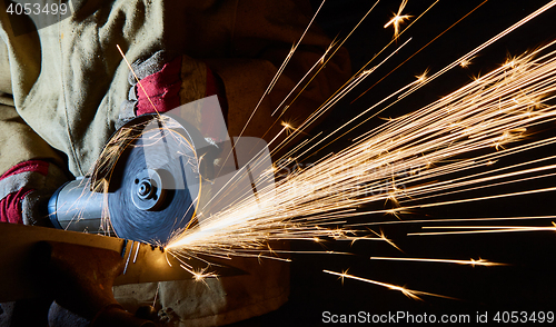 Image of Worker cutting metal with grinder. Sparks while grinding iron