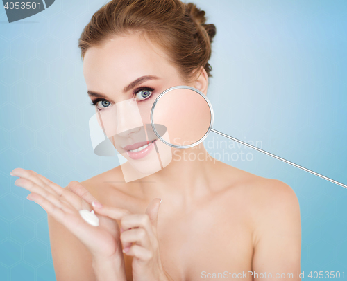 Image of happy young woman with moisturizing cream on hand