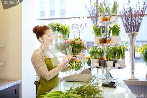 Image of smiling florist woman making bunch at flower shop