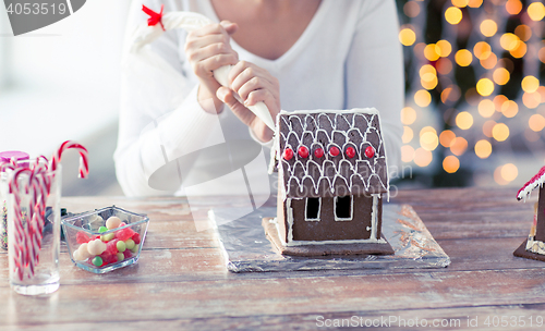 Image of close up of woman making gingerbread house at home