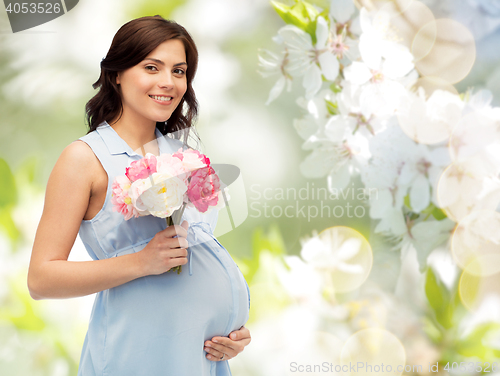 Image of happy pregnant woman with flowers touching belly