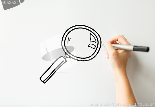 Image of close up of hand writing magnifier on white board