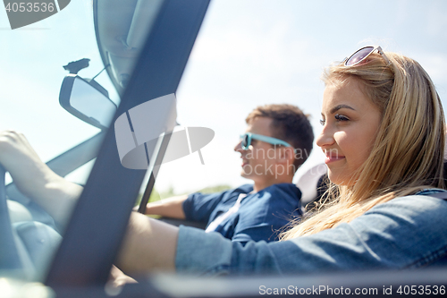 Image of happy couple driving in cabriolet car outdoors