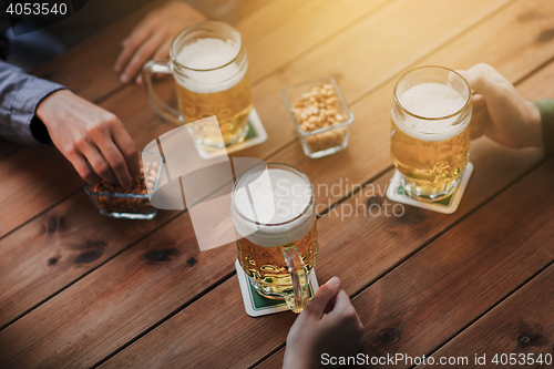 Image of close up of hands with beer mugs at bar or pub