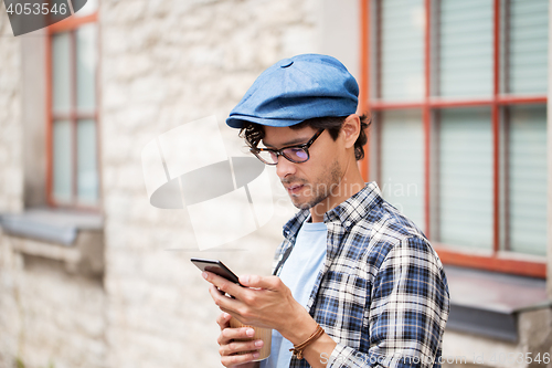 Image of man with smartphone drinking coffee on city street