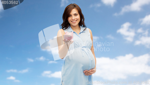 Image of happy pregnant woman with piggybank over blue sky
