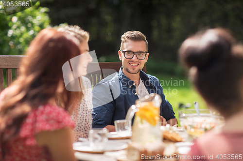 Image of happy friends having dinner at summer garden party