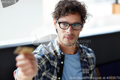 Image of happy man paying with credit card at cafe