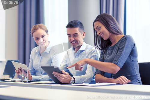 Image of smiling business people with tablet pc in office