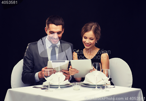 Image of couple with menus on tablet pc at restaurant