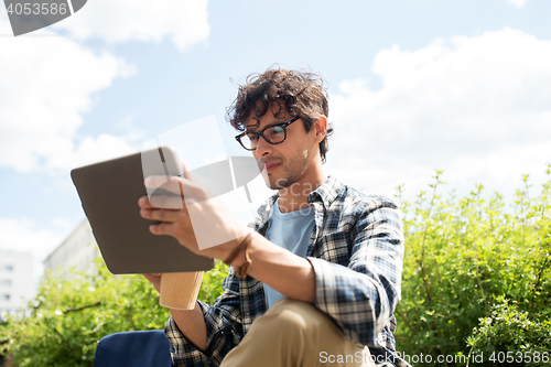 Image of man in glasses with tablet pc on city street 