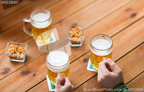 Image of close up of hands with beer mugs at bar or pub