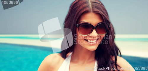 Image of smiling young woman with sunglasses on beach