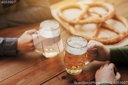 Image of close up of hands with beer mugs at bar or pub